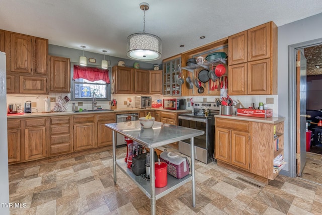 kitchen with a sink, appliances with stainless steel finishes, brown cabinetry, and light countertops