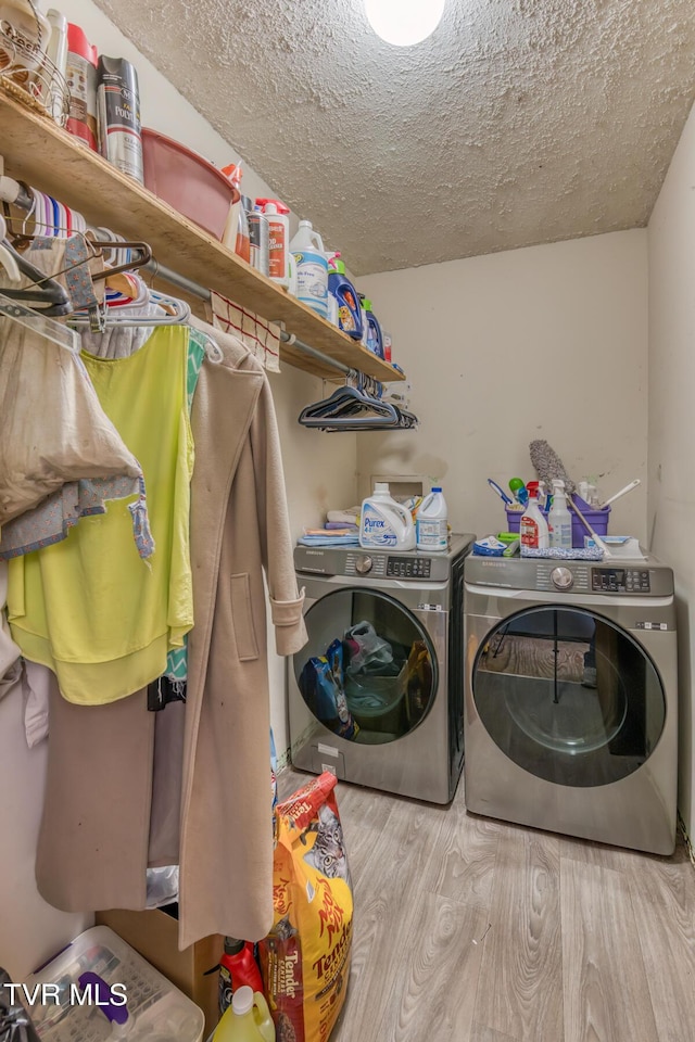 washroom featuring washing machine and clothes dryer, laundry area, a textured ceiling, and wood finished floors