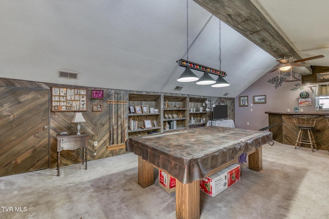 game room featuring carpet floors, wooden walls, a bar, ceiling fan, and vaulted ceiling with beams