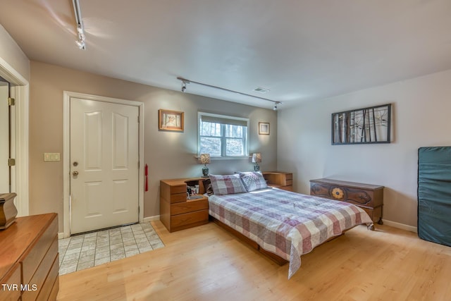 bedroom with visible vents, baseboards, rail lighting, and light wood finished floors
