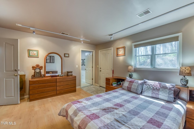 bedroom with rail lighting, visible vents, and light wood finished floors