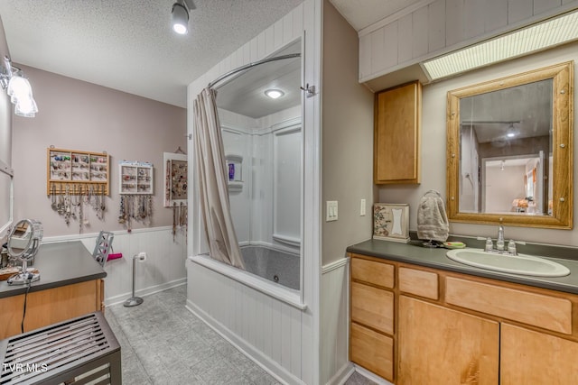 bathroom with tile patterned floors, vanity, a textured ceiling, and wainscoting