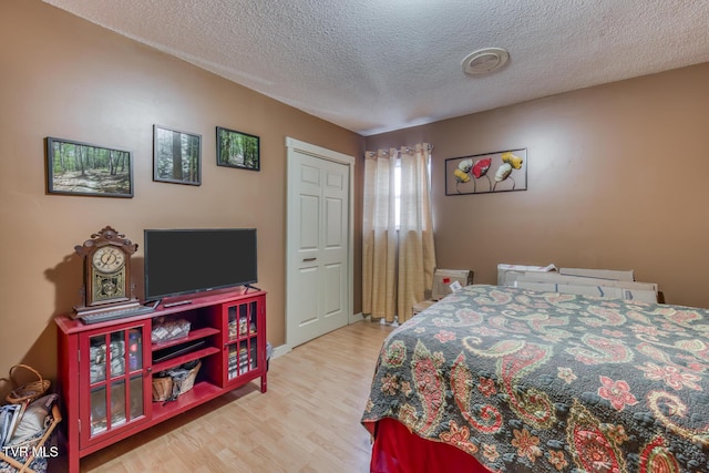 bedroom with a textured ceiling and wood finished floors