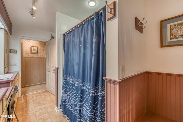 full bath featuring wooden walls, curtained shower, track lighting, wainscoting, and vanity