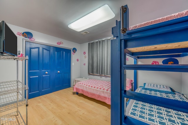 bedroom with wood finished floors, visible vents, and a closet