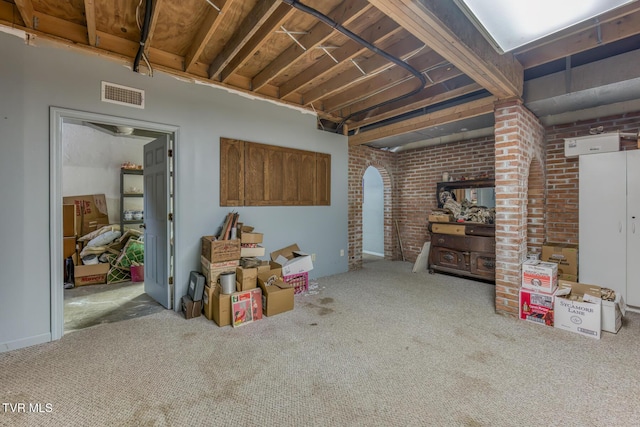 basement with carpet, visible vents, and brick wall