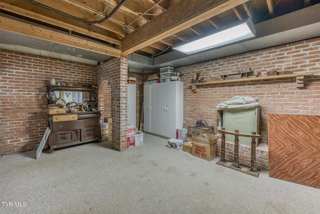 finished below grade area featuring carpet floors, brick wall, and a wood stove