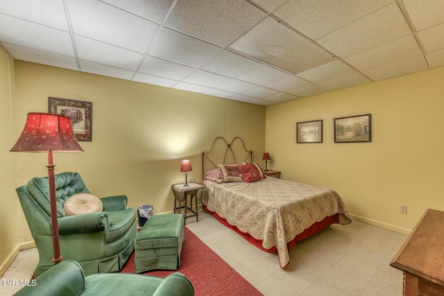 bedroom featuring tile patterned floors, baseboards, and a paneled ceiling