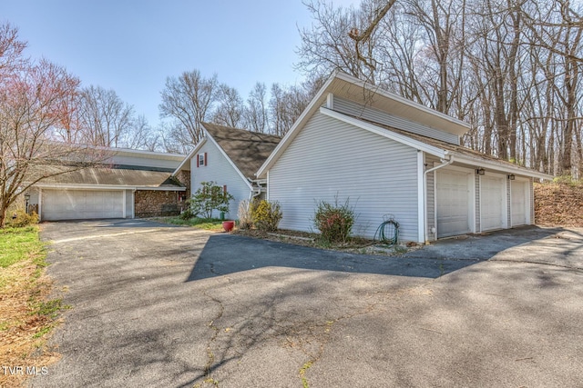 view of side of home featuring a garage and aphalt driveway