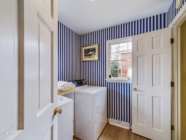 laundry room with washing machine and dryer and wood-type flooring