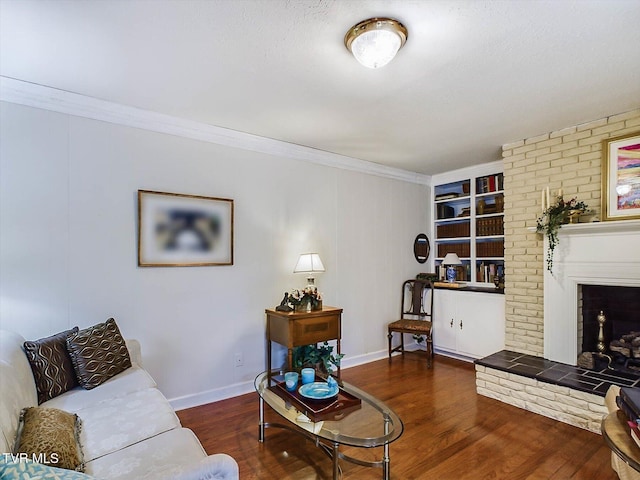 living room with built in shelves, crown molding, dark hardwood / wood-style floors, and a brick fireplace