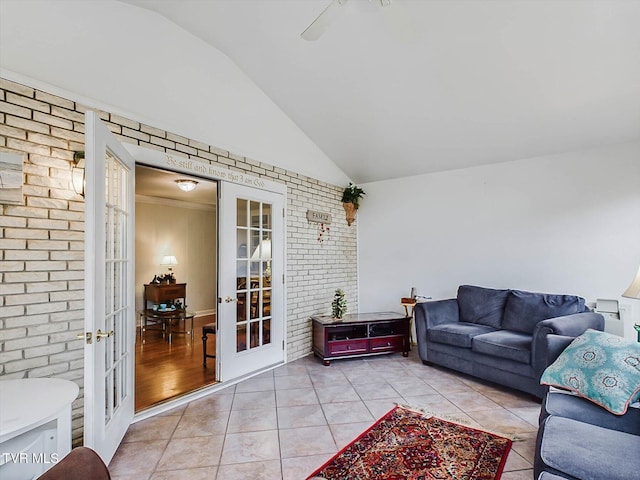 tiled living room featuring ceiling fan, vaulted ceiling, brick wall, and french doors