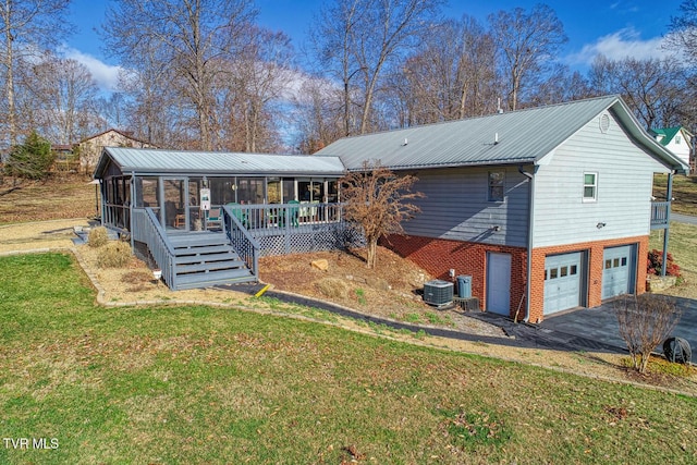 rear view of house with a lawn, a sunroom, a deck, cooling unit, and a garage