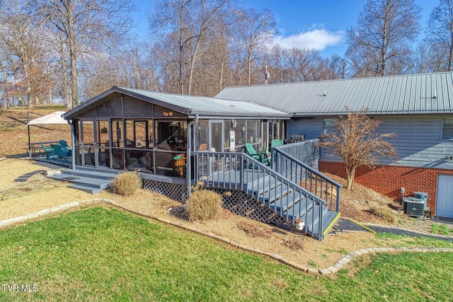 rear view of property with a lawn, a sunroom, cooling unit, and a patio