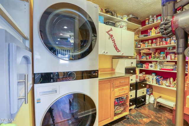 clothes washing area featuring stacked washer / dryer, cabinets, and a textured ceiling