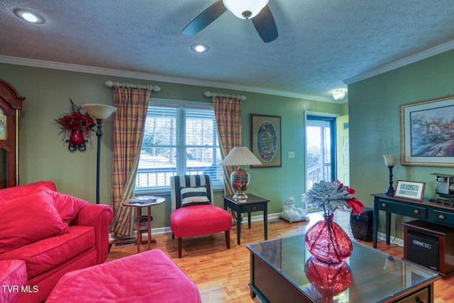 living room with light wood-type flooring, a textured ceiling, ceiling fan, and crown molding