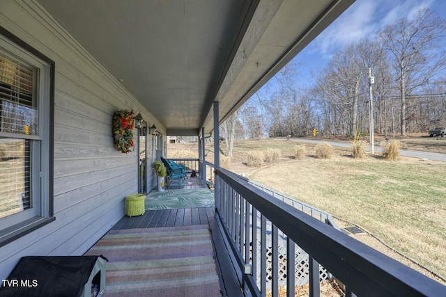 wooden terrace featuring covered porch and a yard