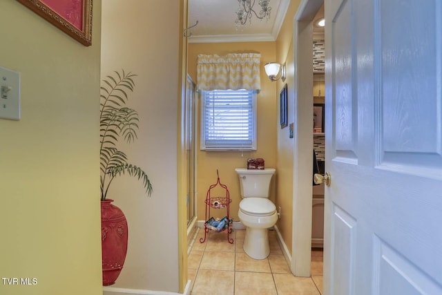 bathroom with toilet, tile patterned floors, a shower with door, and ornamental molding