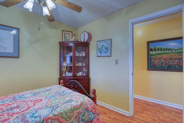 bedroom with ceiling fan, lofted ceiling, and light wood-type flooring