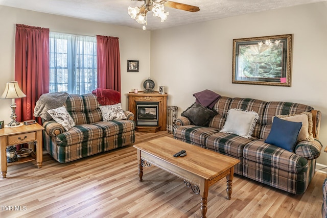 living room with ceiling fan, light hardwood / wood-style flooring, and a textured ceiling