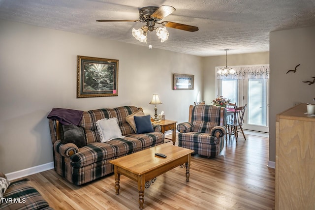 living room with ceiling fan with notable chandelier, light wood-type flooring, and a textured ceiling