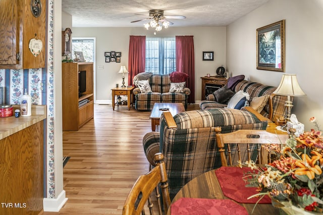 living room with a textured ceiling, light hardwood / wood-style floors, and ceiling fan