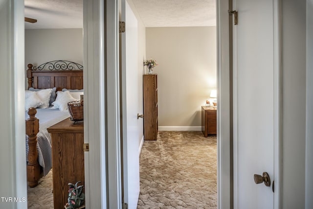 corridor with a textured ceiling and light colored carpet