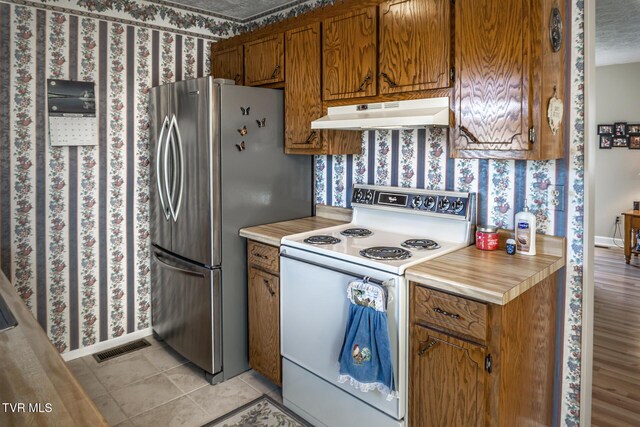 kitchen featuring white range with electric stovetop, stainless steel fridge, and light tile patterned flooring