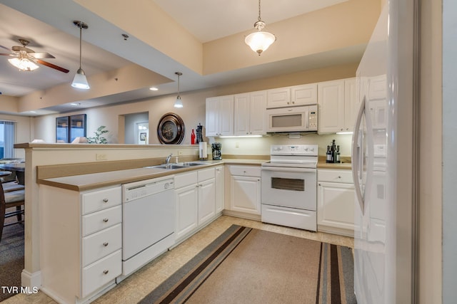 kitchen featuring kitchen peninsula, white appliances, a raised ceiling, sink, and white cabinets