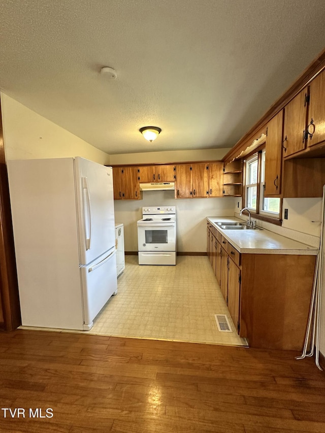 kitchen featuring a textured ceiling, sink, white appliances, and light hardwood / wood-style flooring