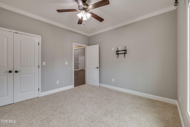 unfurnished bedroom with ceiling fan, a closet, carpet floors, and ornamental molding