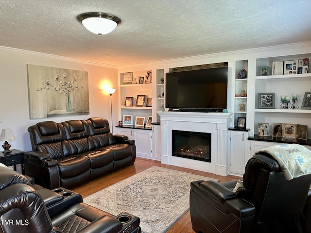 living room with built in shelves, crown molding, light wood-type flooring, and a textured ceiling