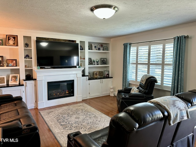 living room featuring built in shelves, a textured ceiling, light hardwood / wood-style floors, and a wealth of natural light