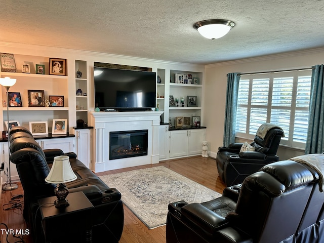 living room featuring plenty of natural light, light wood-type flooring, a textured ceiling, and built in shelves