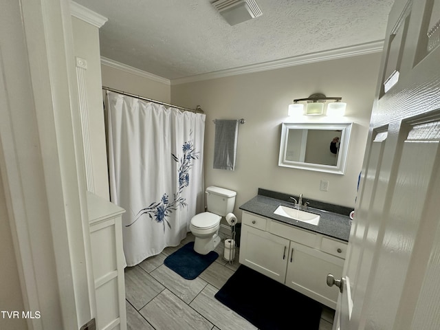 bathroom featuring a textured ceiling, vanity, toilet, and ornamental molding