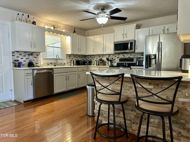 kitchen with a kitchen breakfast bar, a textured ceiling, stainless steel appliances, and white cabinetry