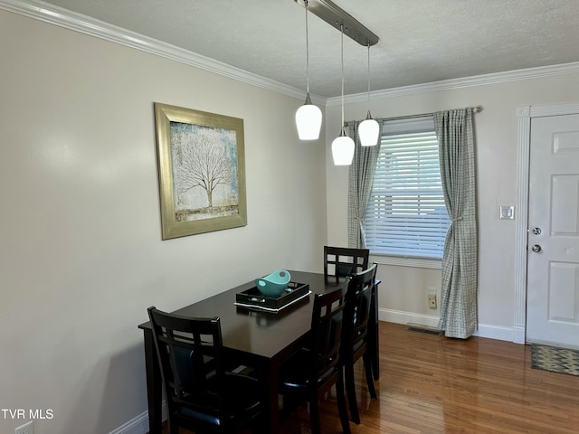 dining room with dark wood-type flooring, a textured ceiling, and ornamental molding