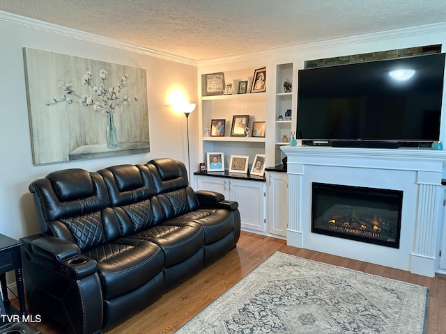 living room with a textured ceiling, light hardwood / wood-style floors, built in features, and ornamental molding