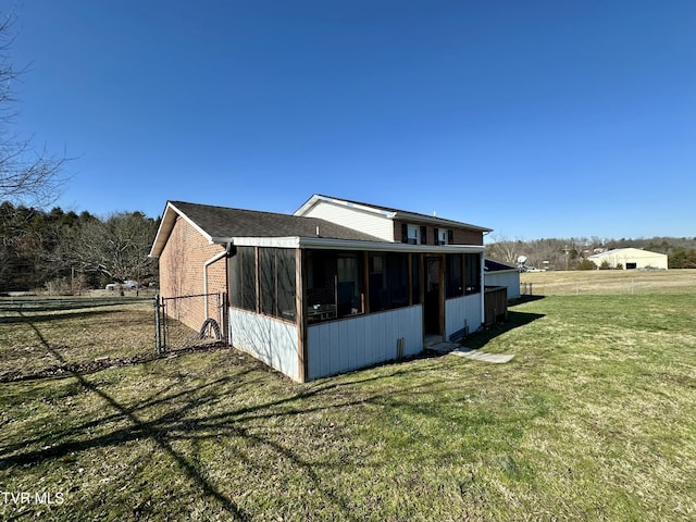 rear view of house featuring a lawn and a sunroom