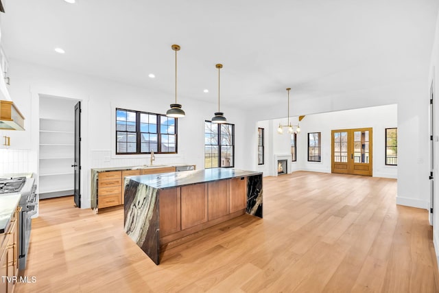 kitchen with a center island, an inviting chandelier, sink, high end stainless steel range oven, and light hardwood / wood-style flooring