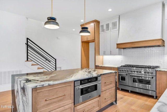 kitchen with pendant lighting, light hardwood / wood-style flooring, light stone counters, white cabinetry, and stainless steel appliances