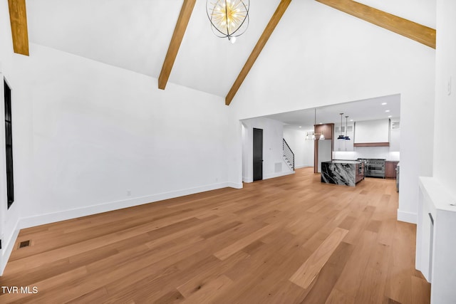 living room featuring beamed ceiling, light wood-type flooring, a chandelier, and high vaulted ceiling