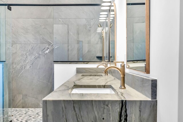 bathroom featuring a tile shower and vanity