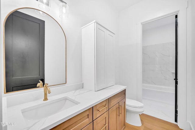 full bathroom featuring hardwood / wood-style flooring, vanity, tub / shower combination, and toilet