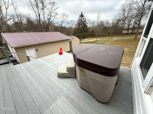 wooden deck featuring an outbuilding, a hot tub, and a lawn