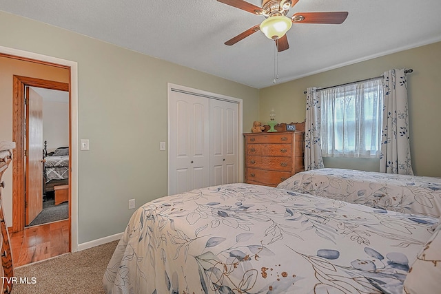 carpeted bedroom featuring ceiling fan, a closet, and a textured ceiling