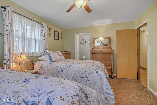 bedroom with ceiling fan, light colored carpet, and a textured ceiling