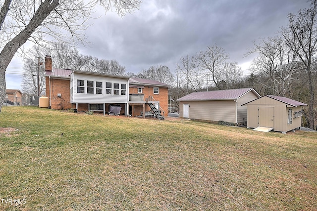 back of house with a lawn, a wooden deck, a sunroom, and a storage shed