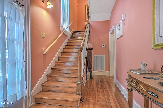 staircase with wood-type flooring and a textured ceiling