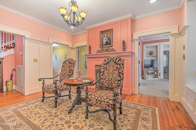 sitting room with crown molding, light hardwood / wood-style floors, and a chandelier